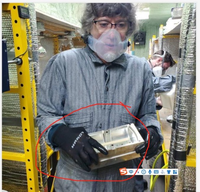 Eileen Durfee wearing a respirator and holding the aluminum mold for a foam roller in the production shop