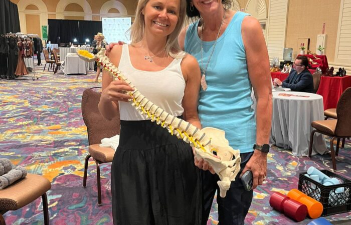 Eileen Durfee holding a spine model while teaching at a wellness event