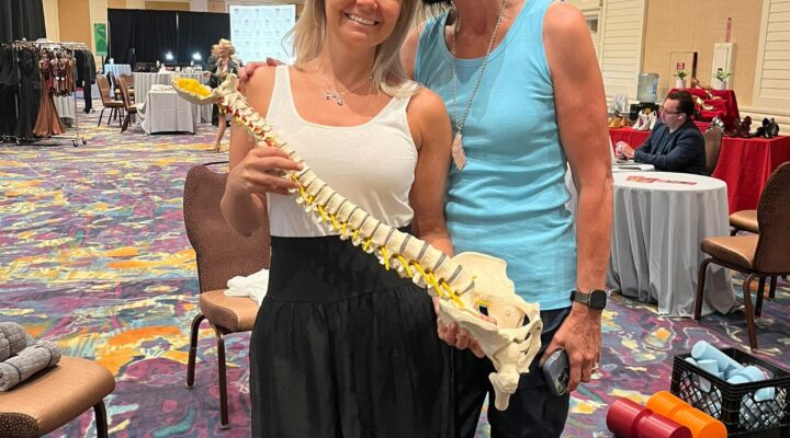 Eileen Durfee holding a spine model while teaching at a wellness event
